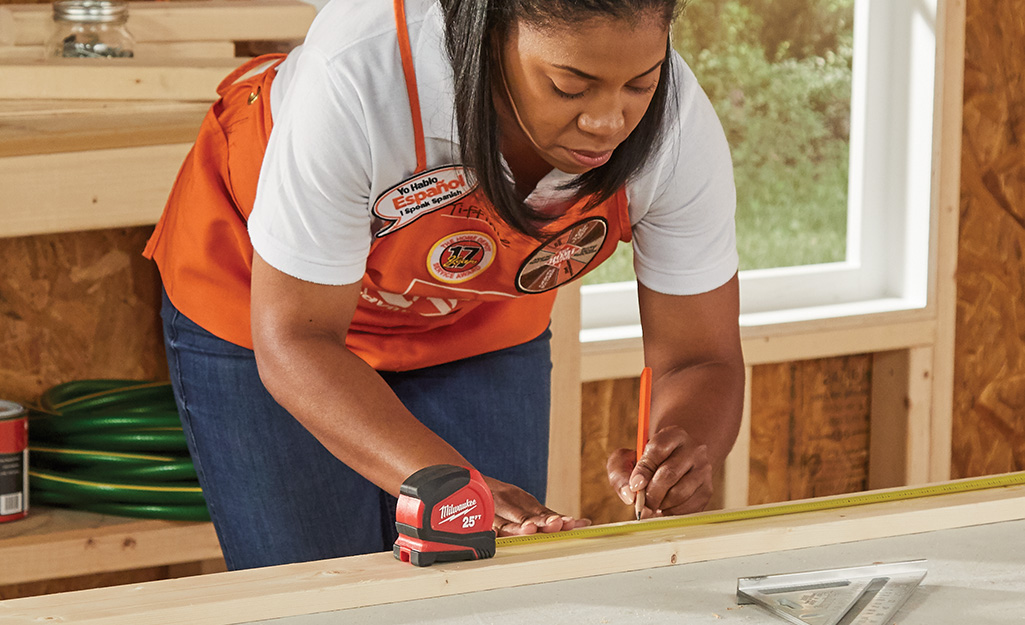 A woman measures her boards with measuring tape. A woman measures her boards with measuring tape.