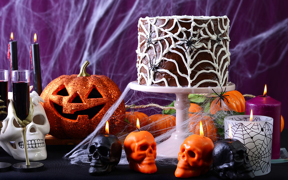 A table decorated for halloween with a spider web cake.