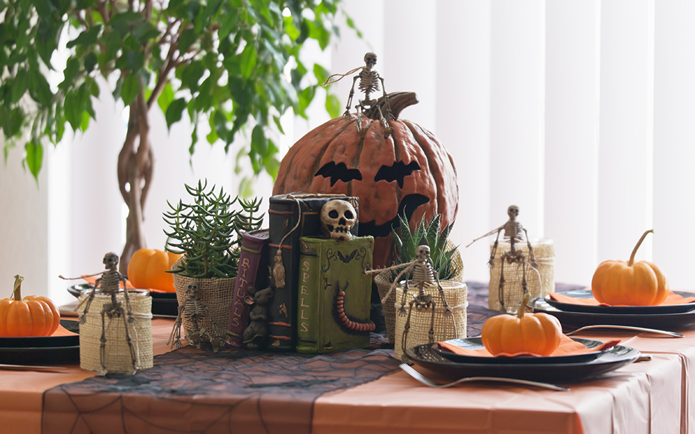 A table decorated for halloween with squash and skeletons.