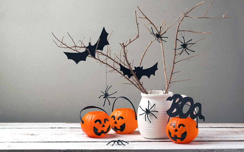 A halloween centerpiece made with a jar, twigs and bats.