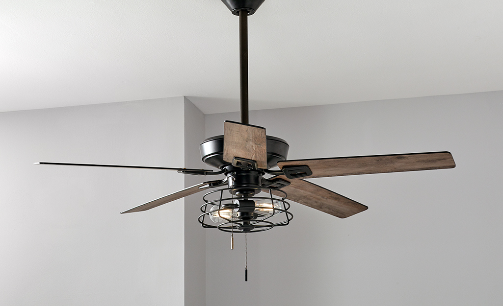 A brown Hampton Bay ceiling fan with three down lights.