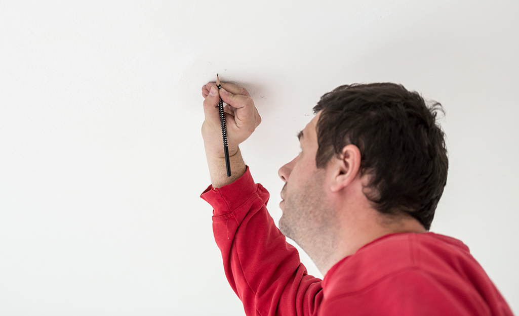 A person marks the spot to install a mounting bracket.