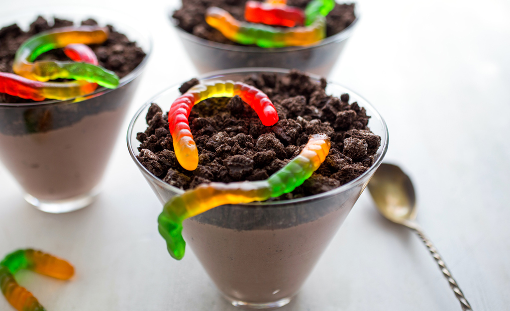 Dirt cup dessert with pudding, cookie crumbles and gummy worms.
