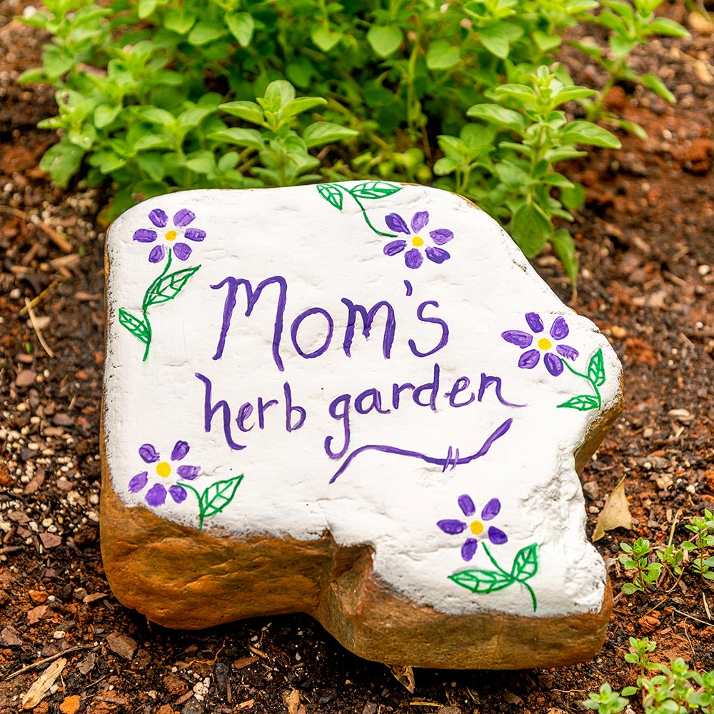 A large painted rock in a garden.