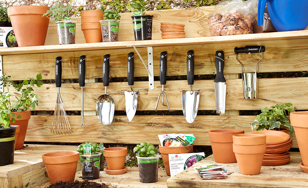 A potting bench with terra cotta pots, tools and herb plants
