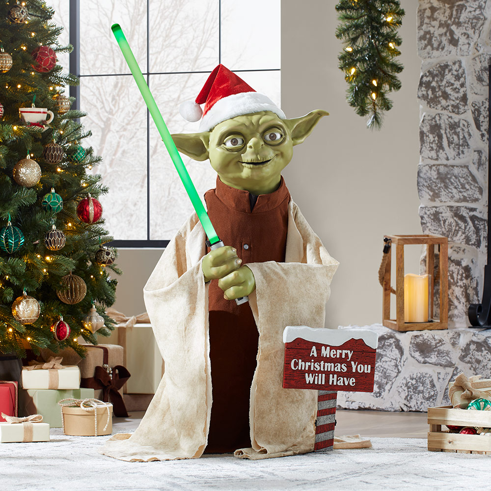 A holiday themed animatronic Yoda figure near a Christmas tree.