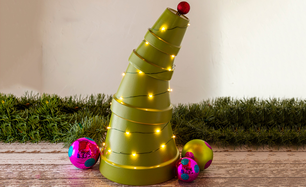 A terra cotta pot Christmas tree with lights twined around it.