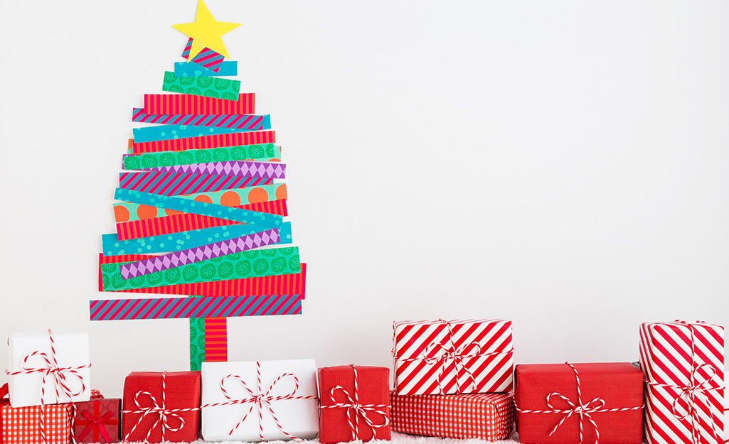 Presents sit beneath a depiction of a Christmas tree on the wall made from different patterns of washi tape.