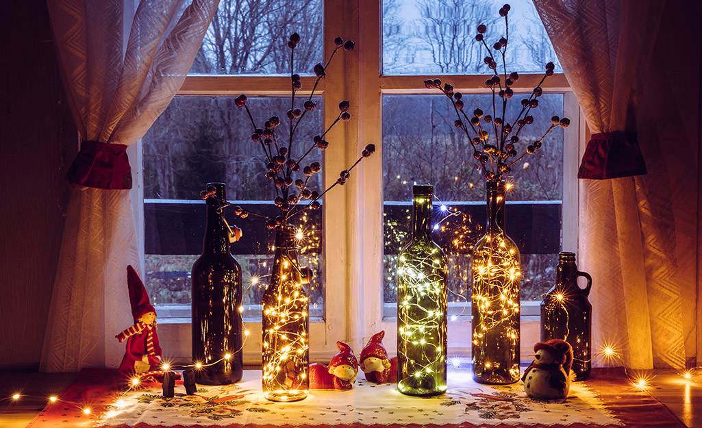 Wine bottles filled with holiday lights and branches with berries.