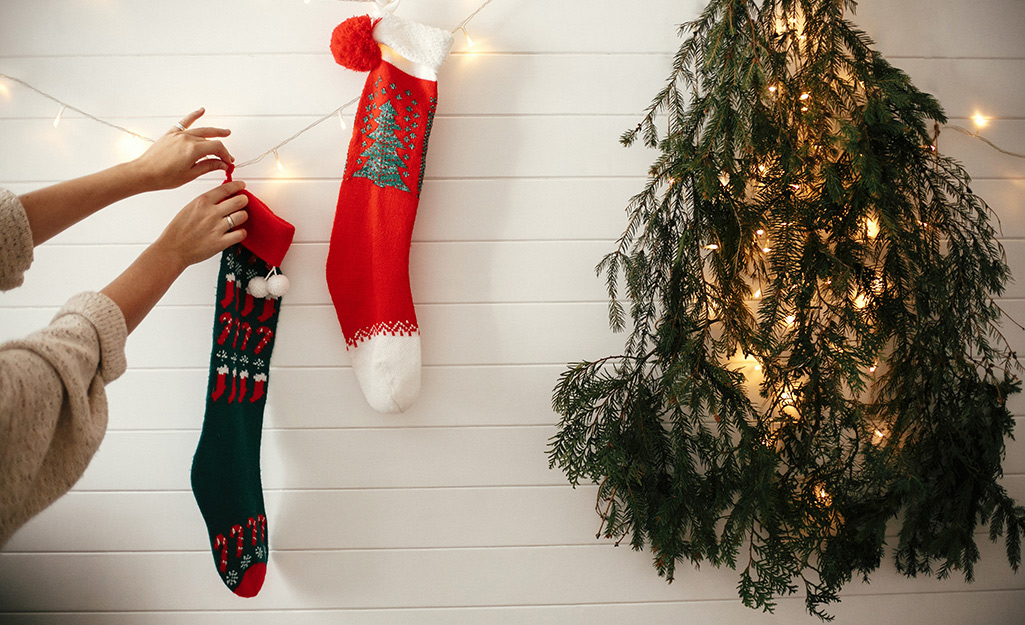 A person hangs stockings on a strong along a wall.