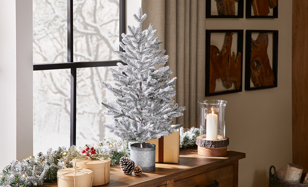 A tabletop Christmas tree sits in front of a window.