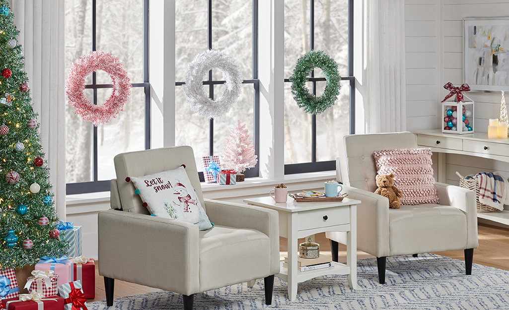 Three wreaths hang on windows in a living room.