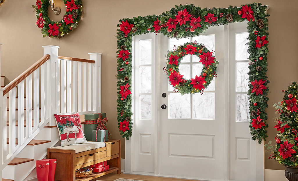 A garland of greenery and poinsettias draped around a doorway.