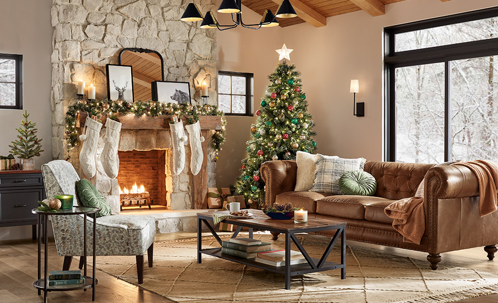 Stocking hang in front of stone fireplace next to a Christmas tree in a room with a leather couch and a window showing a snowy view.