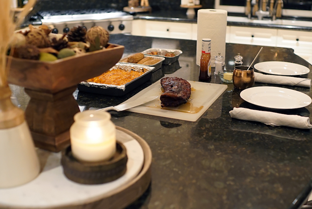 A tablescape featuring wood accents, a candle, and freshly smoked food from the Masterbuilt Electric Smoker.