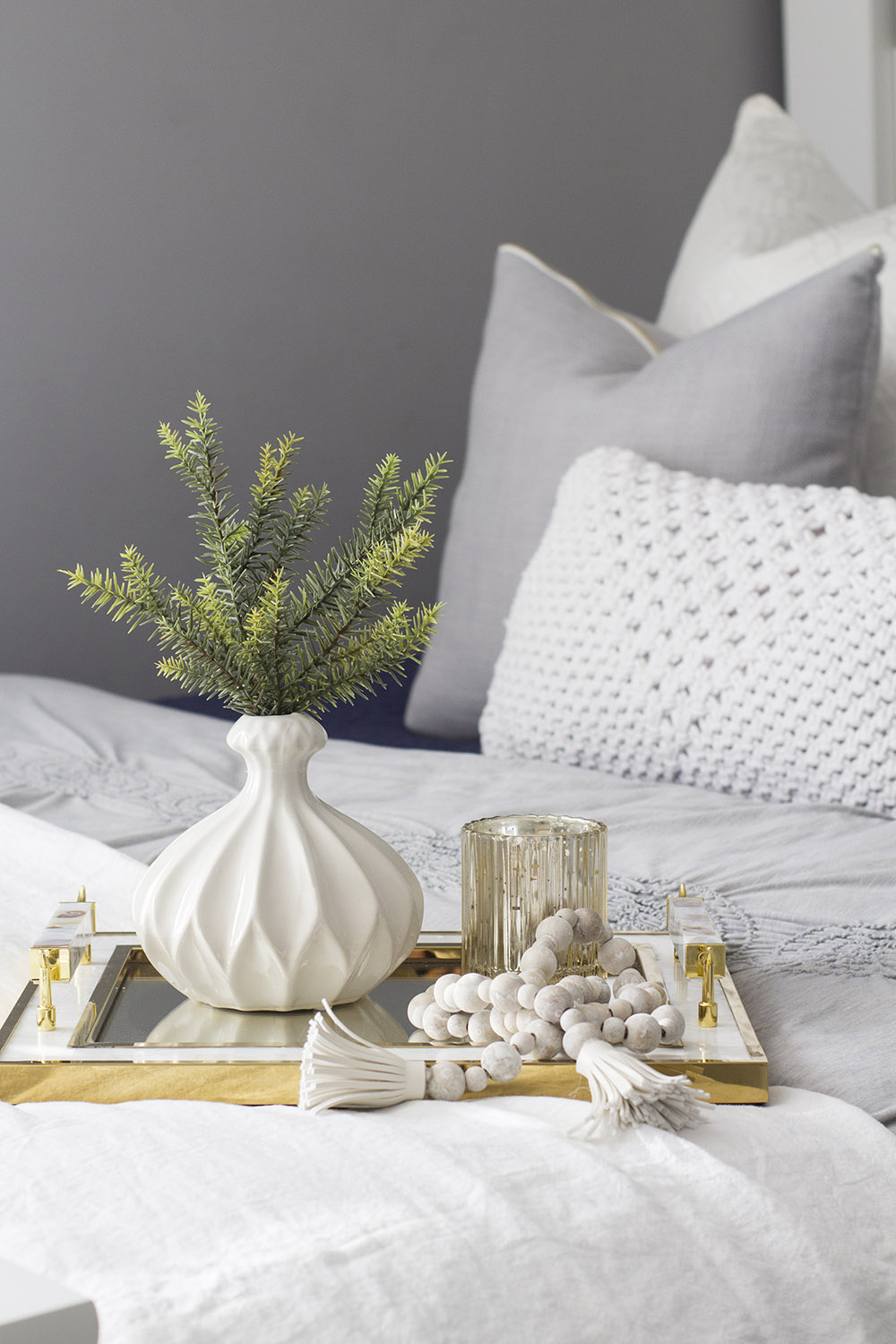 A mirrored tray with gold handles is decorated with a vase and candle. A mirrored tray with gold handles is decorated with a vase and candle.
