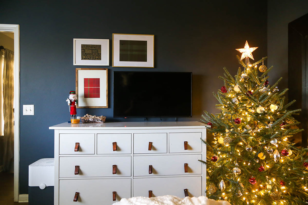 The corner of a bedroom is decorated by a lighted Christmas tree with ornaments.. The corner of a bedroom is decorated by a lighted Christmas tree with ornaments..