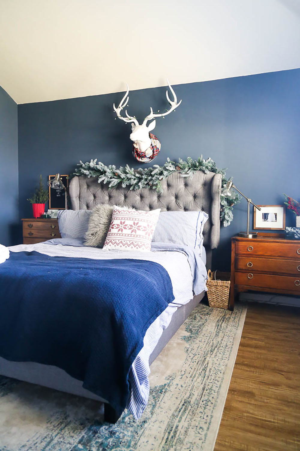 The headboard of a bed is decorated for the holidays with garland.