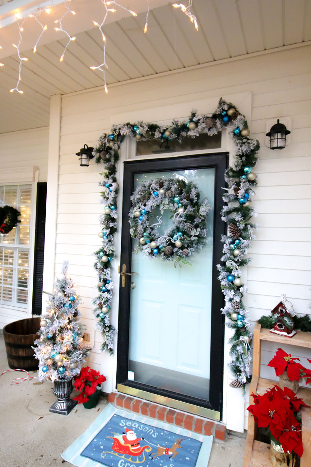 A front door with a flocked holiday wreath decorated with blue and gold ornaments. A front door with a flocked holiday wreath decorated with blue and gold ornaments.