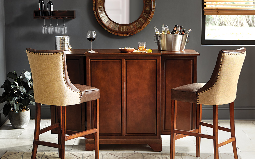 Two leather and upholstery stools provide seating at a brown wood home bar.