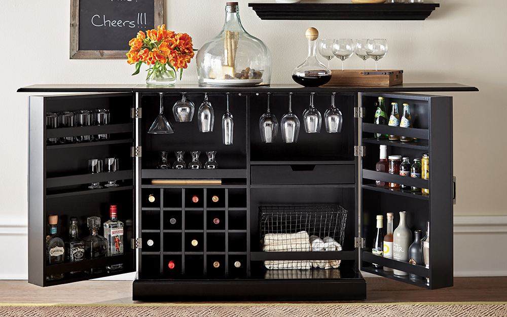 A dark colored bar with wine glasses and alcohol.