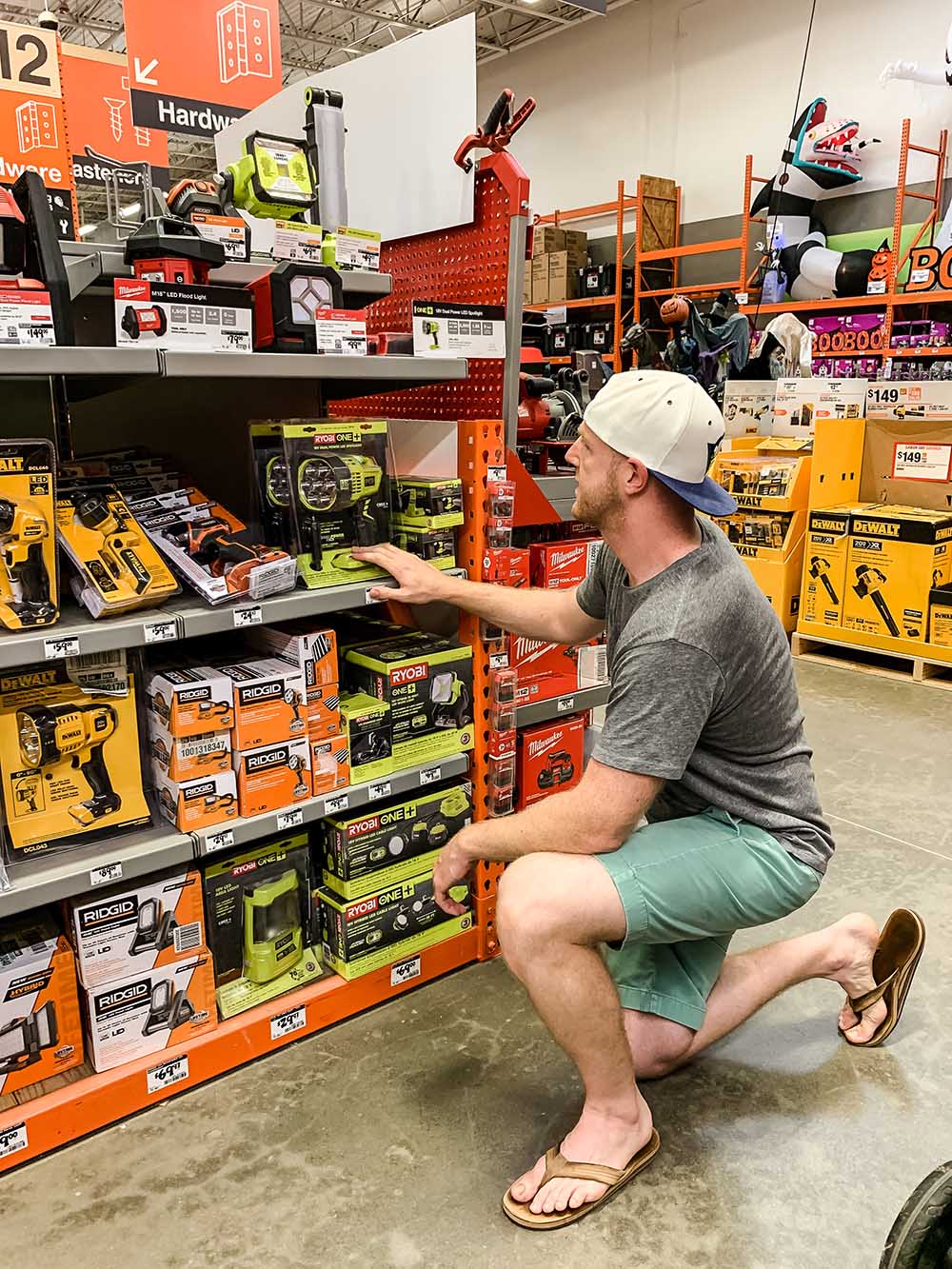 A man kneels in front of a shelf of products in The Home Depot.