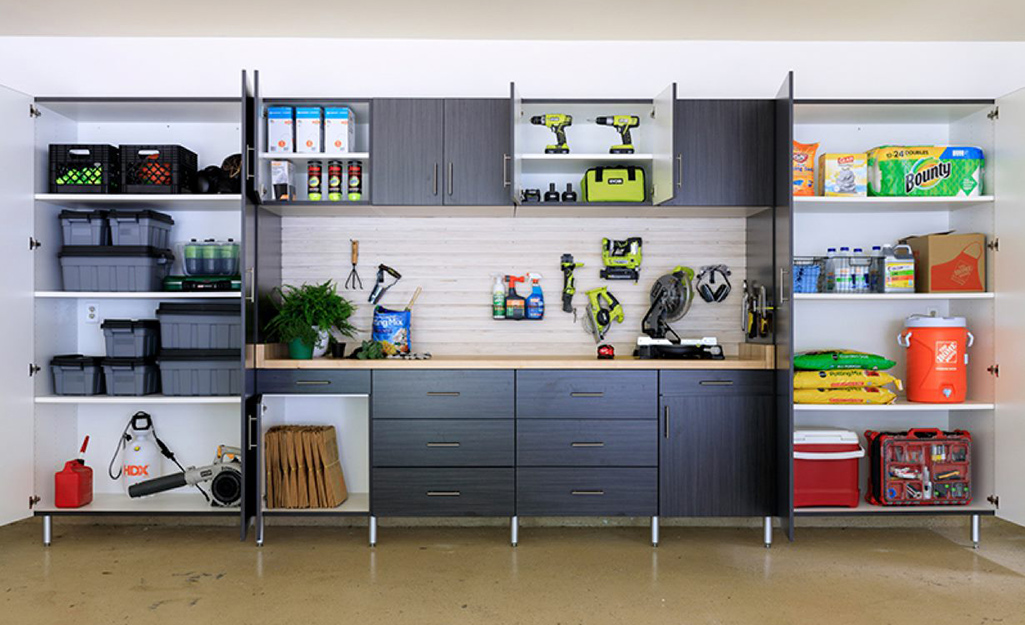 An organized garage features cabinets to store tools and outdoor equipment.