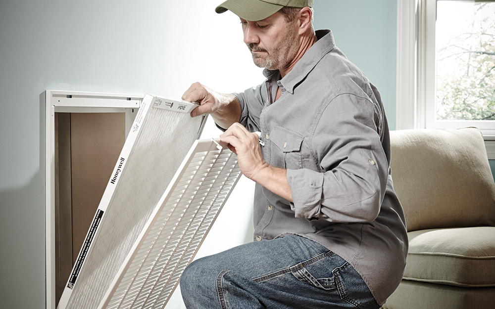 a man replacing an air filter inside the home