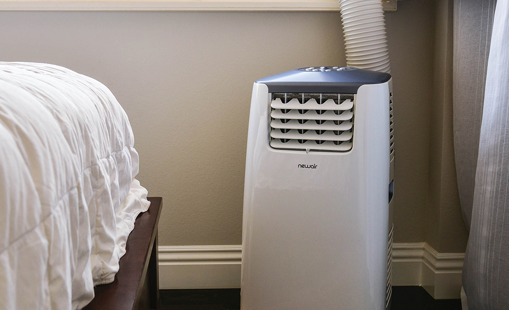 A white single hose portable air conditioner vented to the outside through a window.