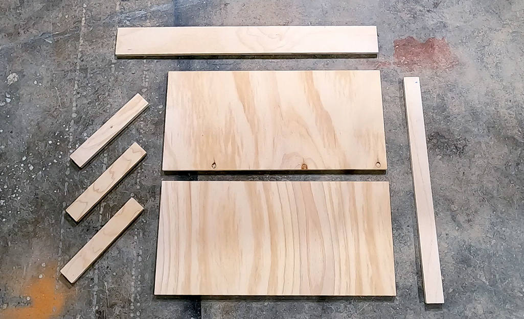 Cut pieces of plywood laid out for the DIY desk project.
