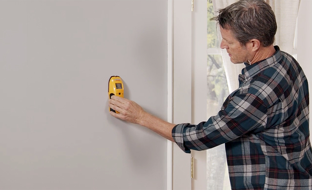 A person using a stud finder on a wall.