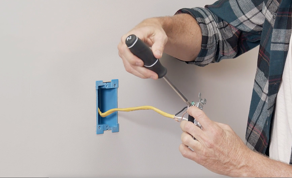 A person connecting the wires in a switchbox.