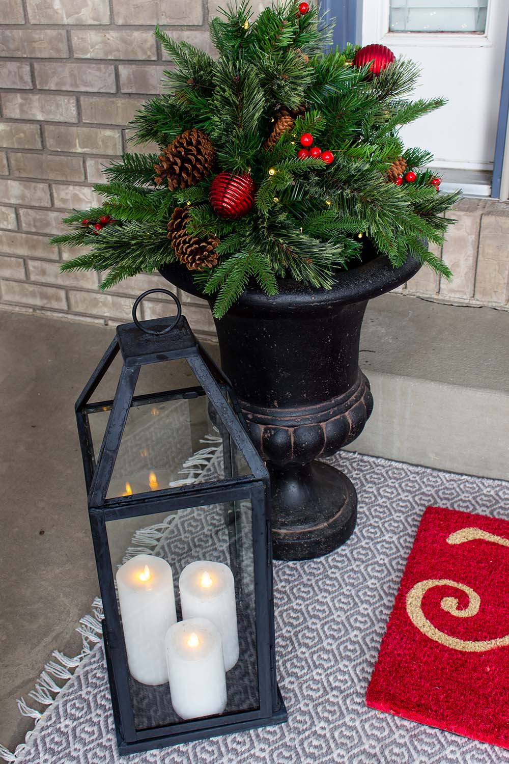 Lantern next to Christmas decor on front porch 
