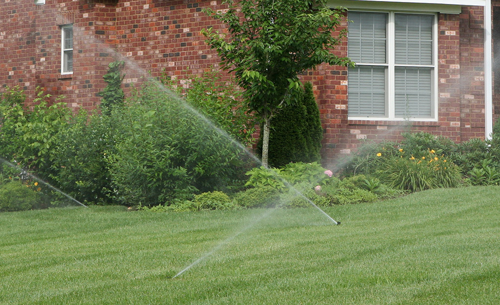 A lawn being watered by an in-ground irrigation system.