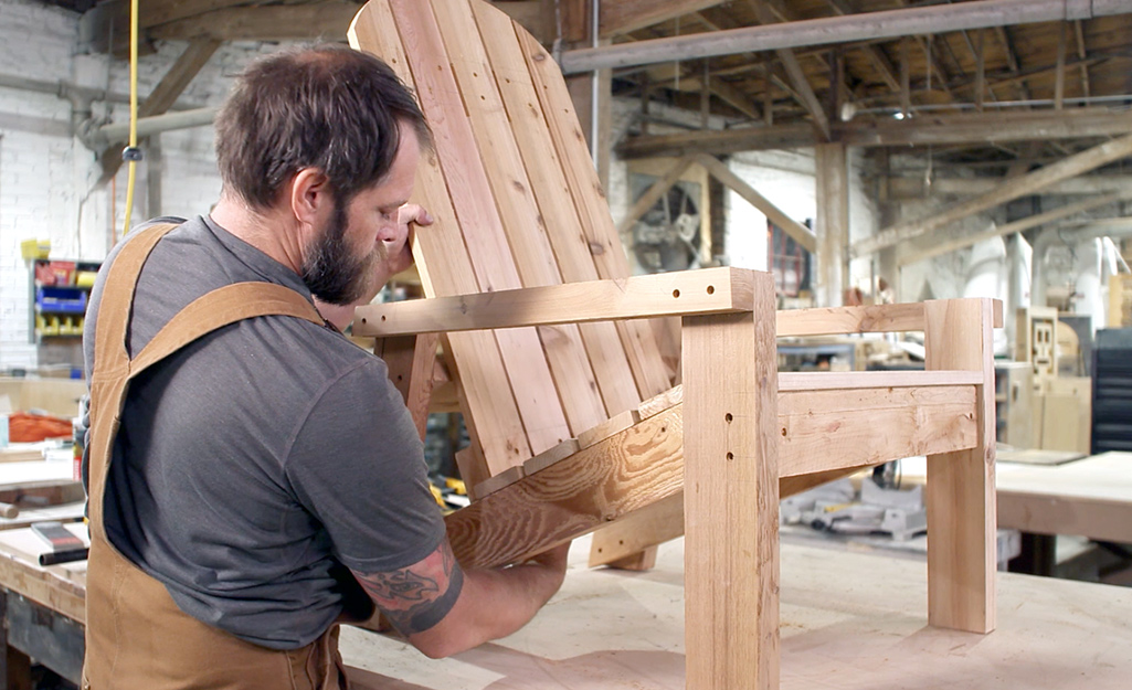 A person attaching the back of an Adirondack chair.