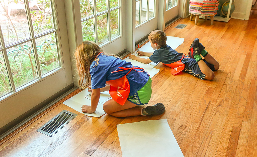 Two kids drawing on paper on the floor. Two kids drawing on paper on the floor.