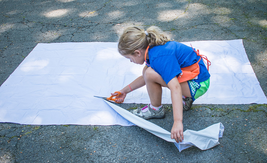 A young girl cutting a piece of curtain. A young girl cutting a piece of curtain.
