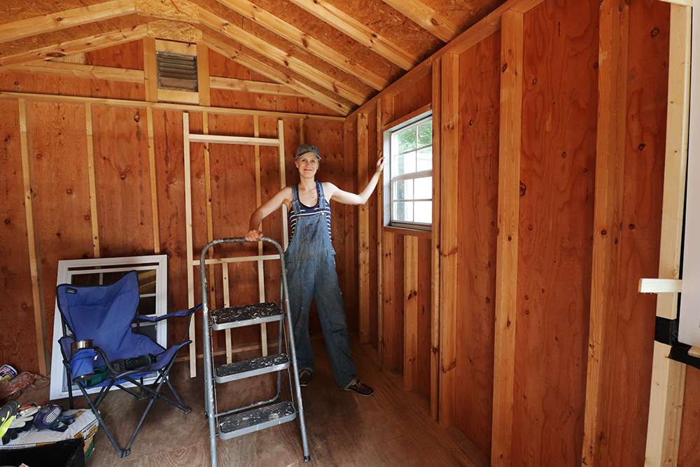 A person standing in the corner of a wooden barn