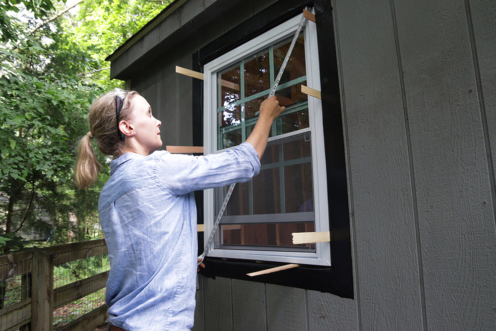A person installing a window with shims 