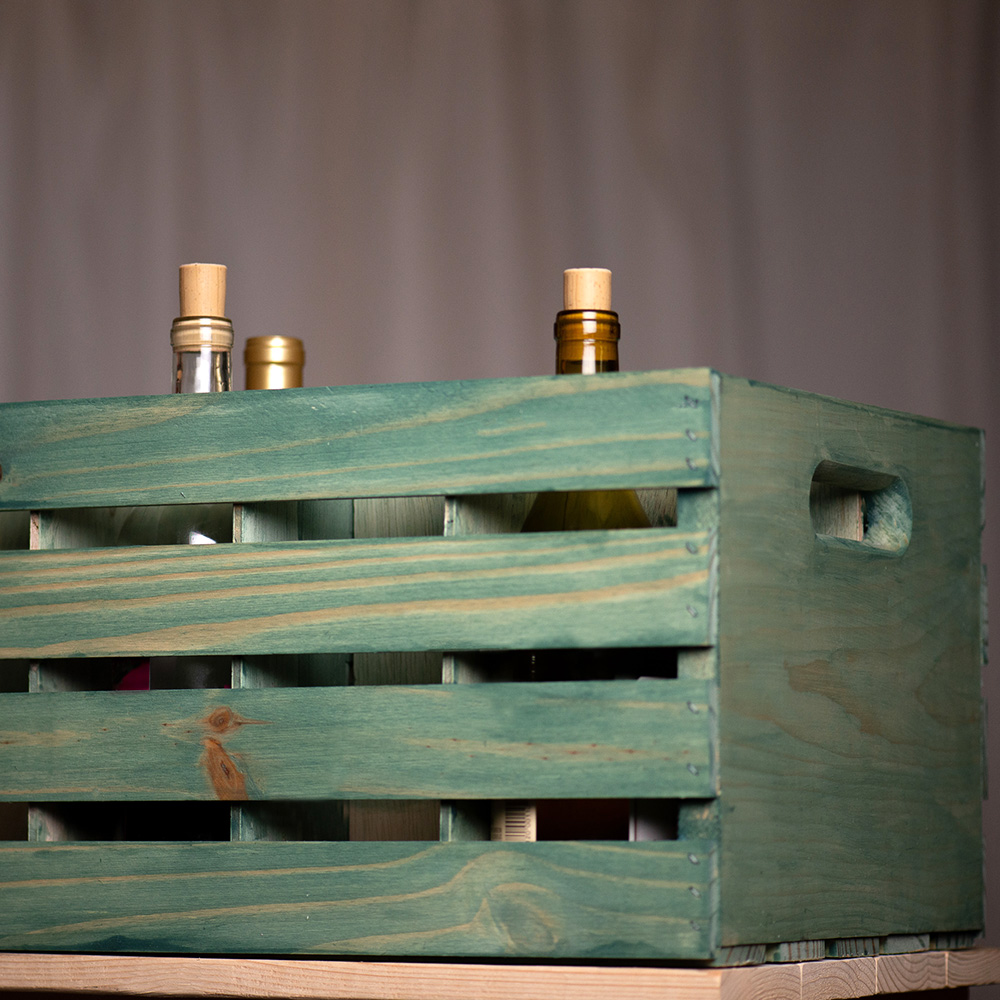 A green beverage crate with several wine bottles in it. How to Build a Beverage Crate.
