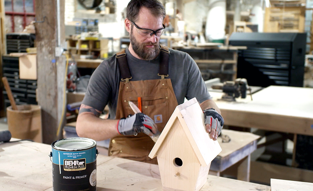 A person paints the roof of the birdhouse.