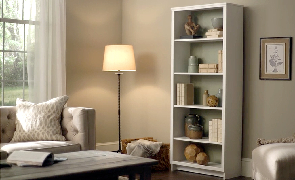 A five-shelf bookshelf stands in a furnished living room.