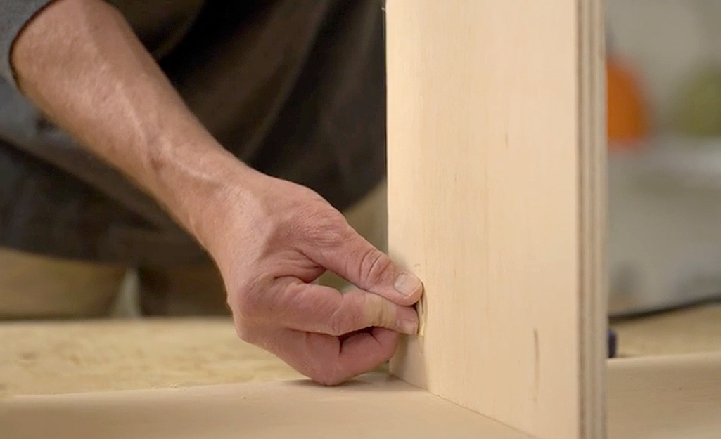 Someone inserting pocket hole plugs into a board to hide screws.