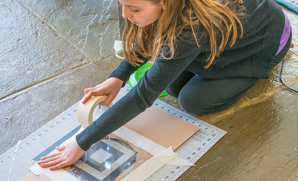 A person building a skylight for a deluxe cardboard playhouse.