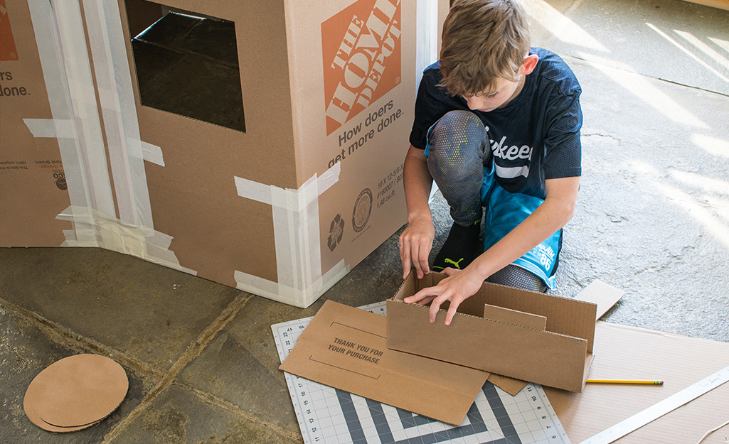 A child assembling a cardboard window box.