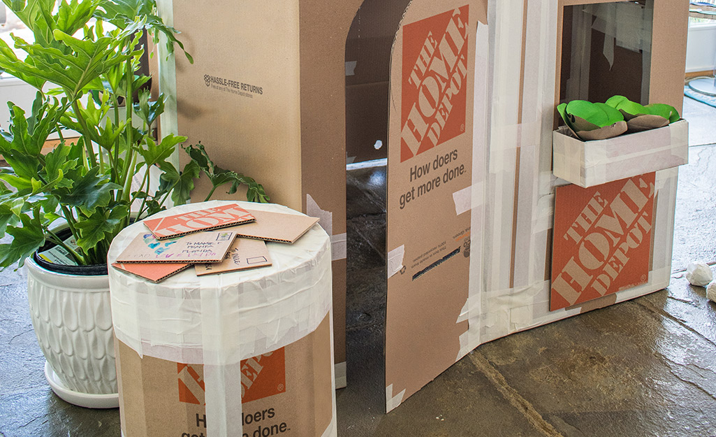 A cardboard play ottoman next to a cardboard playhouse.