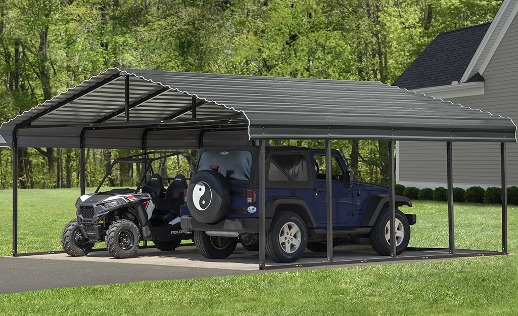 A Jeep and an ATV part side-by-side in a metal carport.