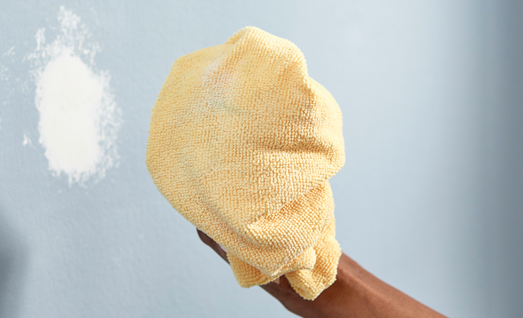 A wall is cleaned using a cloth.