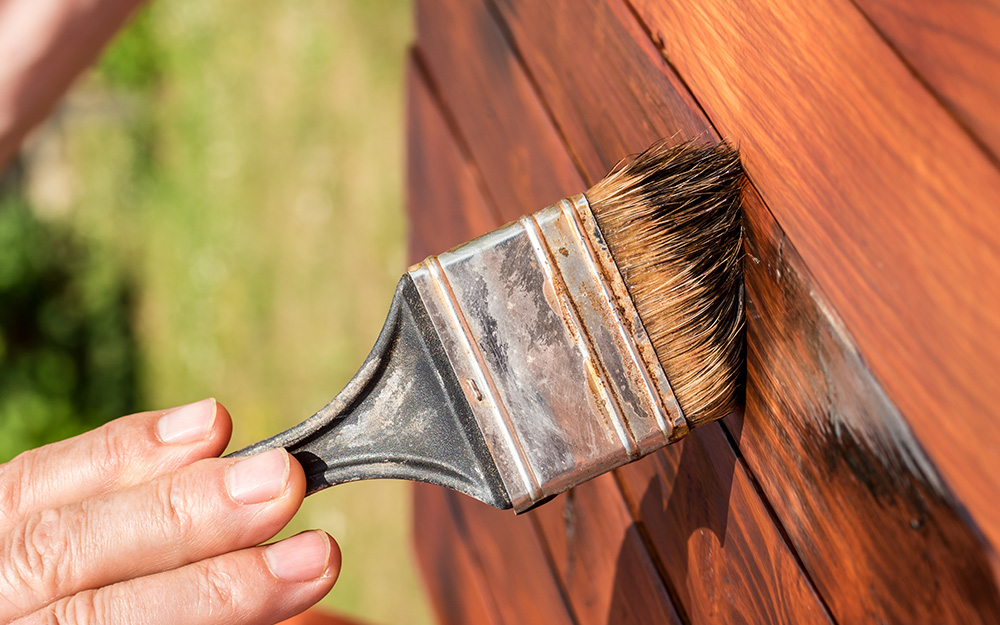 A person staining wood A person staining wood