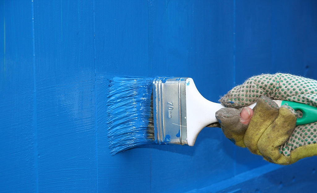 Someone painting a chicken coop blue. Someone painting a chicken coop blue.